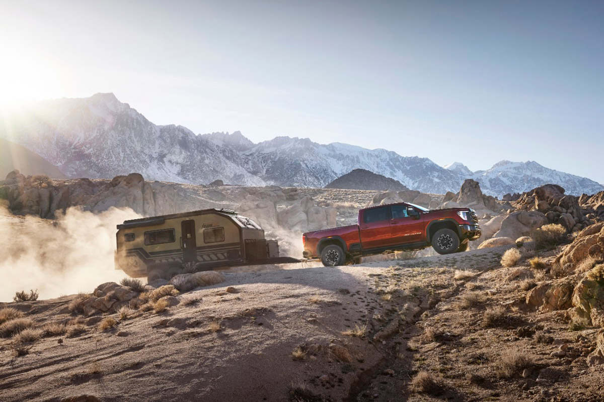 2024 GMC Sierra 2500HD AT4X towing a trailer through rocky mountain terrain