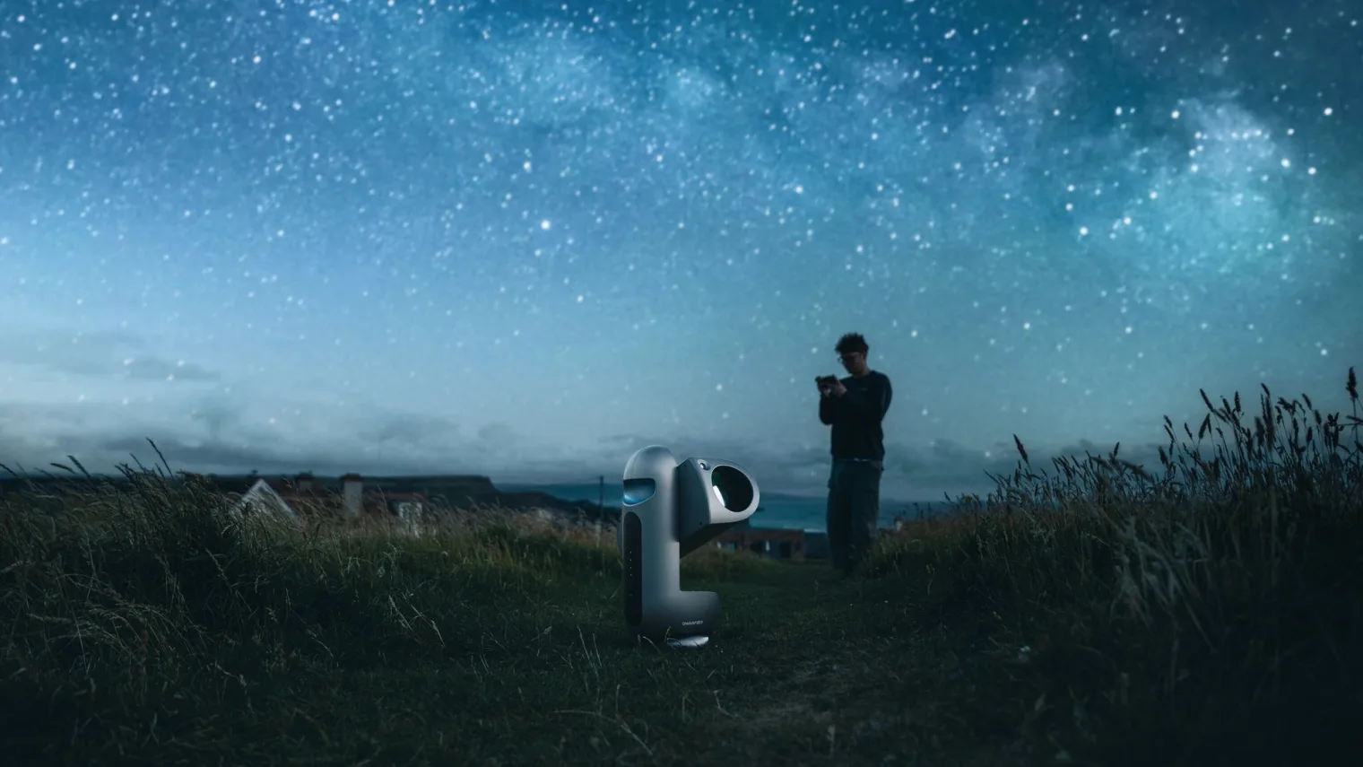 DWARFLAB Draco smart telescope set up in a field under a starry night sky, official lifestyle image