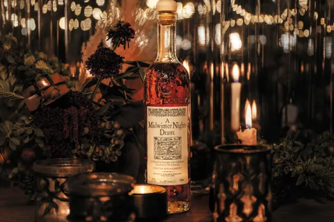 High West A Midwinter Night's Dram Act 14 whiskey bottle with its label visible, in warm candlelight