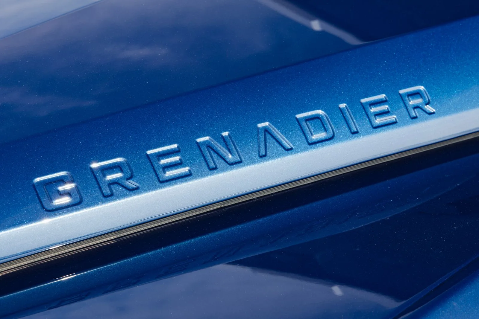 Close-up of the embossed Grenadier badge on Whiteout Blue paint