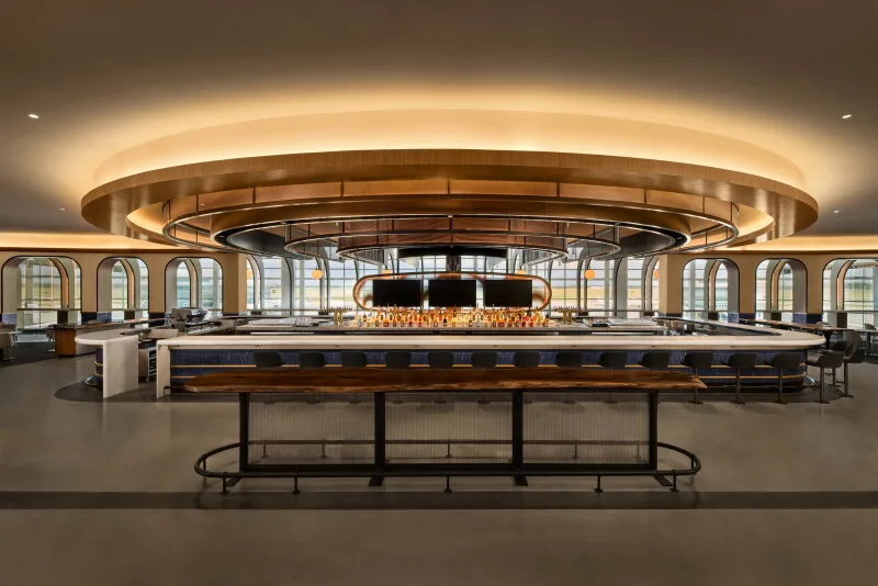 The main full-service bar at United's new Houston United Club, with a large round glowing light fixture
