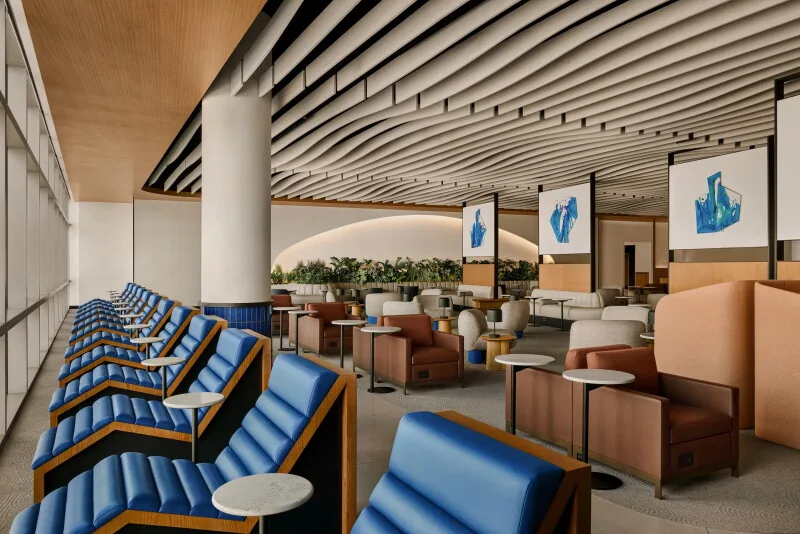 Blue-cushioned lounge seats by a wall of windows at United's new Houston United Club