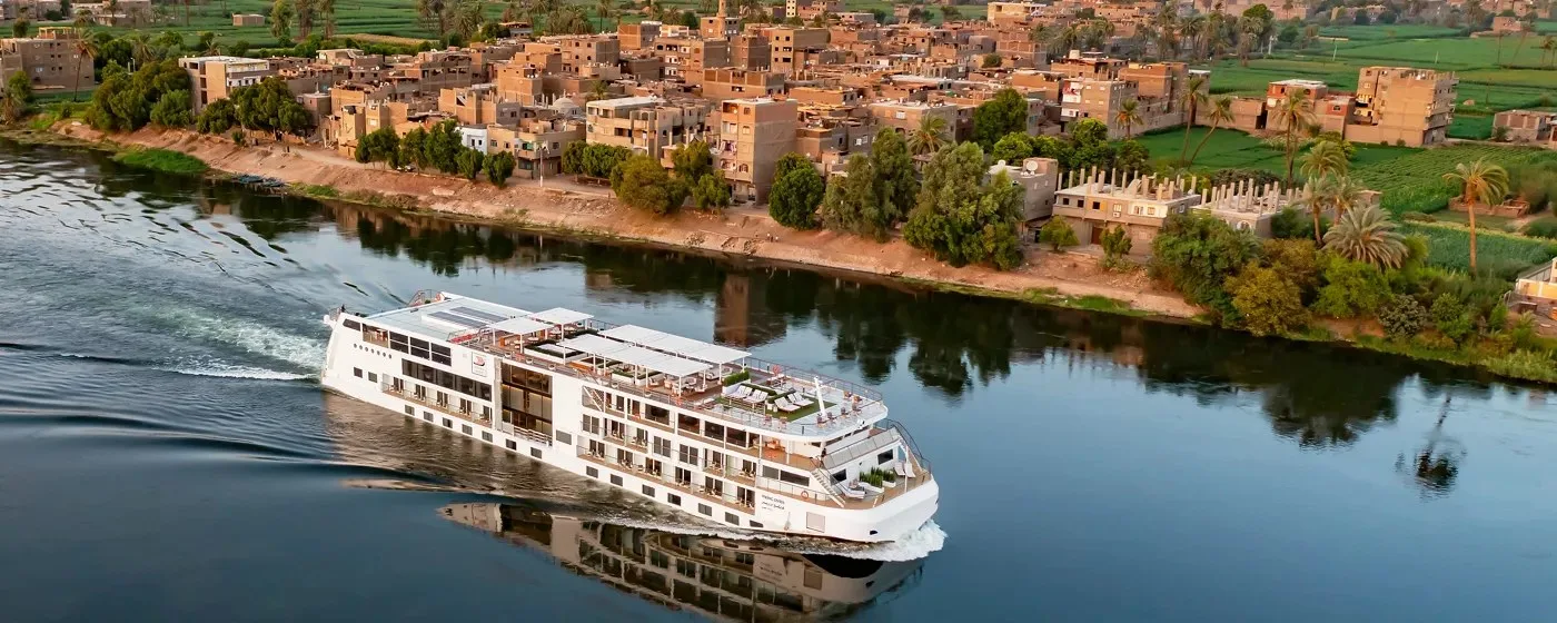 Viking Osiris sailing past a Nile village in Egypt The Viking Osiris river ship sailing past a village on the Nile in Egypt